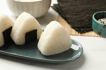 Tasty onigiri (Japanese rice balls) on white table, closeup