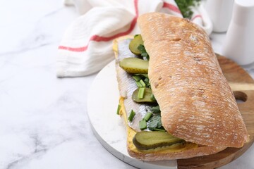 Tasty sandwich with herring, pickles, green onions and parsley on white marble table, closeup....