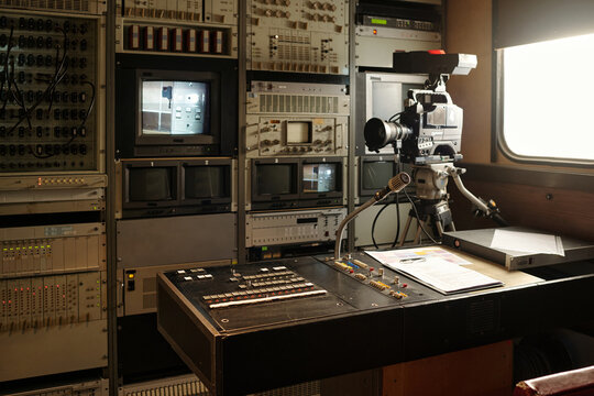 Sound mixing console standing in the center of TV news production truck with professional video camera and other equipment