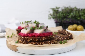 Tasty sandwiches with herring and horseradish sauce on white table, closeup