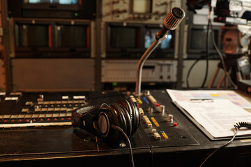 Microphone on sound mixing console with headphones, script on paper document and broadcast schedule...