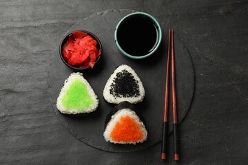 Tasty tobiko onigiri (Japanese rice balls) served on black table, flat lay