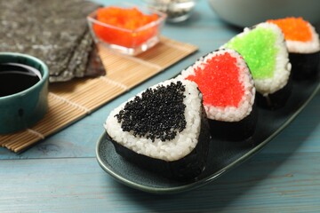 Tasty tobiko onigiri (Japanese rice balls) served on light blue wooden table, closeup