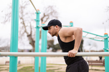 Man dips exercising on parallel bars in park workout station.