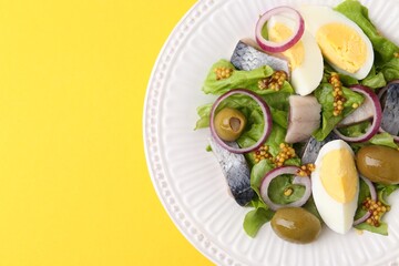 Delicious salad with herring, egg, mustard and vegetables on yellow background, top view. Space for text