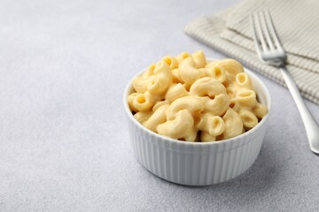 Delicious pasta with cheese sauce and fork on grey table, closeup. Space for text