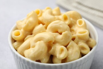 Delicious pasta with cheese sauce in bowl on table, closeup