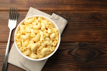 Delicious macaroni and cheese served on wooden table, top view. Space for text