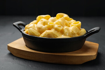Delicious macaroni and cheese on black table, closeup