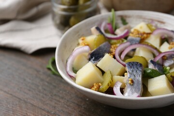Delicious salad with herring, vegetables and mustard in bowl on wooden table, closeup. Space for text