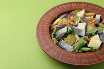 Delicious salad with herring, vegetables and mustard on green background, closeup. Space for text