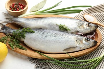 Salted herrings and spices on white wooden table, closeup