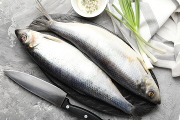 Salted herrings, spices and knife on grey table, flat lay