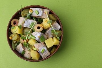 Delicious salad with herring on green background, top view. Space for text
