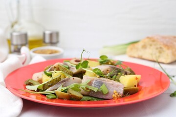 Delicious salad with herring on white tiled table, closeup