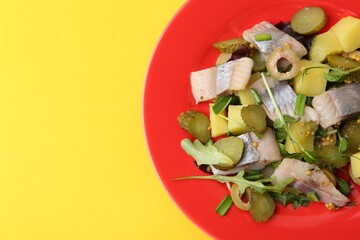 Delicious salad with herring on yellow background, top view. Space for text