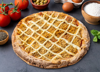 Chicken and Catupiry cream cheese pizza over stone background with flour, olives, tomatoes and eggs