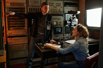 Young man pointing at screen with new record and explaining female colleague details of video...