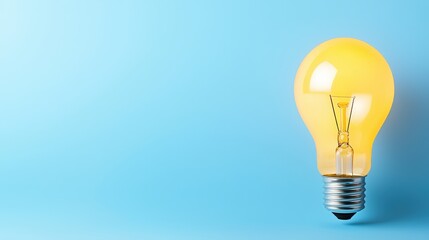 A bright yellow incandescent light bulb glows against a light blue background providing ample copy space for your design projects or presentations.