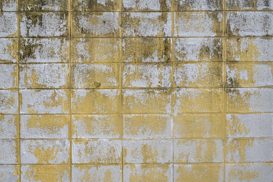 A dirty, dilapidated stone wall divided into rectangles, with yellow tints