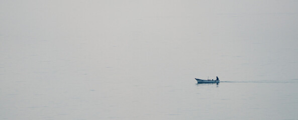 A fisherman sailing alone on a gray day