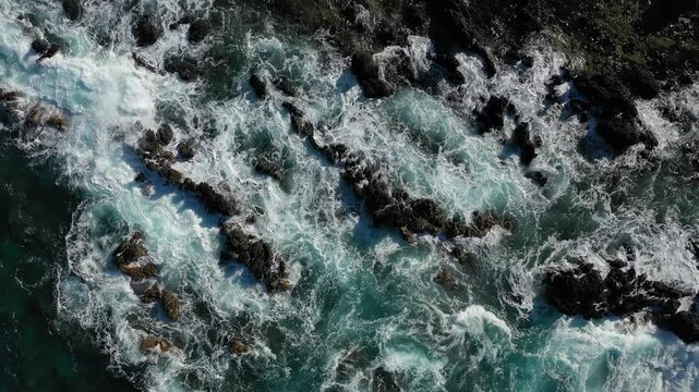 drone photo of ocean waves crashing on the rocks