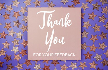 Thank you for your Feedback text on paper card with star glitter decoration flat lay on purple background