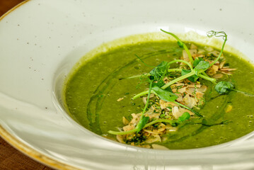 Close-up of green vegetable soup with almonds and microgreens
