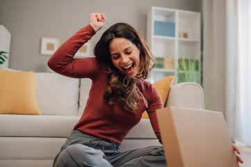 Excited woman celebrating while unboxing a package at home