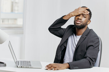 Stressed office worker struggling with workload, sitting at desk with laptop and head in hands