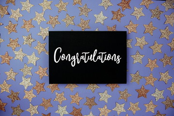 Congratulations text on paper card with star glitter decoration flat lay on purple background
