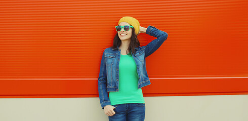 Happy smiling young woman in summer posing against colorful wall on city street