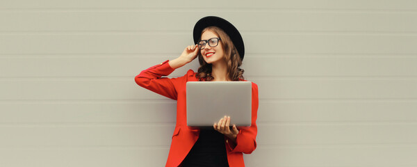 Happy modern young woman working on a laptop, freelancer girl with computer looking away