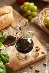 A bottle of balsamic vinegar with Italian ciabatta bread, grapes, walnuts and basil