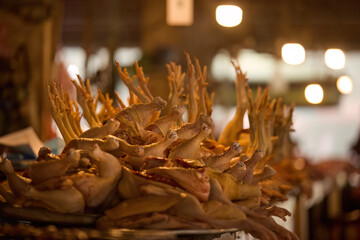 Freshly butchered chickens with raised feet displayed in a traditional market under warm lights. Ideal for: illustrating raw meat trade, food markets in Asia, culinary culture, and poultry farming.