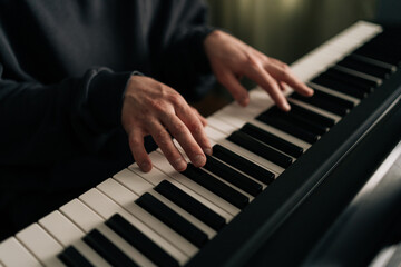 Close-up hands of unrecognizable male composer playing synthesizer in living room. Closeup of talented musician creating beautiful melodic composition using digital piano at home studio.