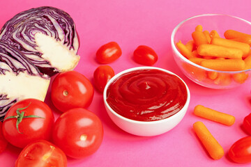 Tasty ketchup and vegetables on pink background, closeup