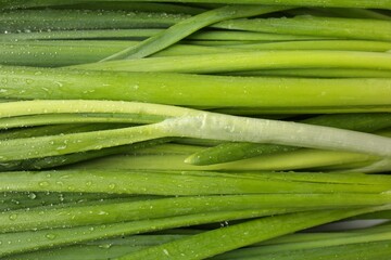 Fresh green onions with water drops as background, top view