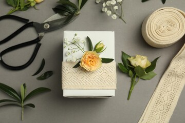 Florist. Box, flowers, leaves and scissors on grey background, flat lay