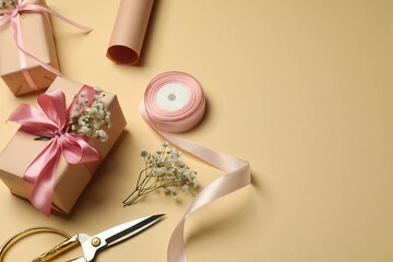 Florist. Boxes, flowers, ribbon and scissors on beige background, space for text