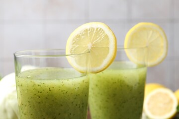 Healthy parsley drink in glasses with lemon slices on blurred background, closeup