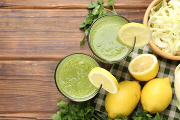 Healthy parsley drink in glasses, lemons and cabbage on wooden table, flat lay. Space for text