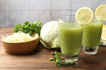 Healthy parsley drink in glasses, lemons and cabbage on wooden table, closeup