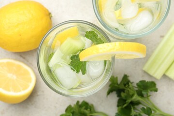 Healthy drink with parsley, lemons and celery on light grey table, flat lay