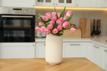 Bouquet of beautiful tulips in vase on wooden table indoors