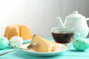Pieces of delicious bundt cake, Easter eggs and tea on light blue wooden table