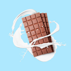 Yummy chocolate bars and splashes of milk in air on light blue background
