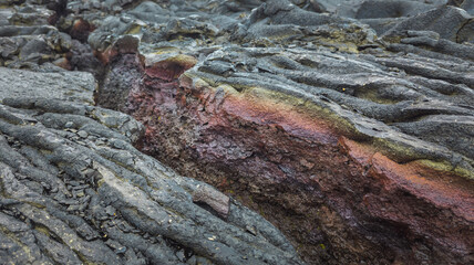 Close-up of a cooled lava flow from the Fagradalsfjall volcano, showing black crust and vibrant minerals beneath, ideal for geology-related visuals.