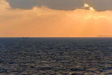 Fototapeta premium 夕焼けに染まる海と遠くの船影