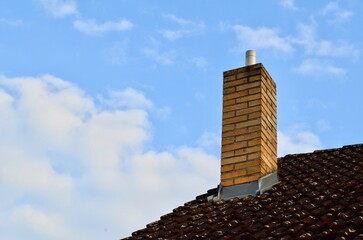 roofing roof of a house with a pipe and blue sky chimney on the roof of a house